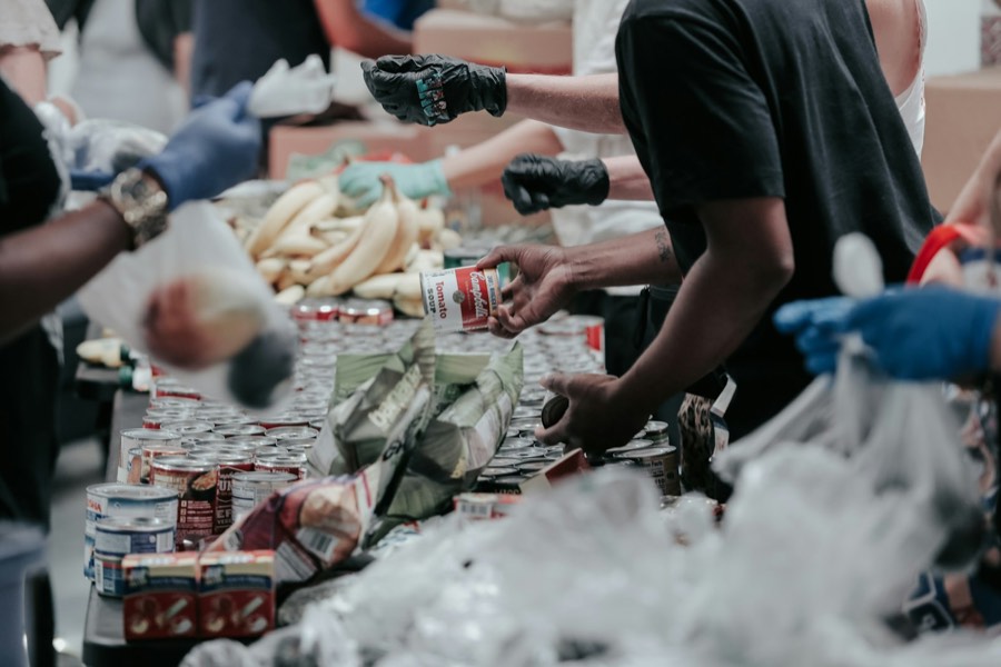Volunteers sorting canned goods and fresh produce along a distribution table.